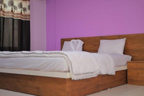 a bedroom with a wooden bed with white sheets and pillows at The dream gir farm in Junagadh