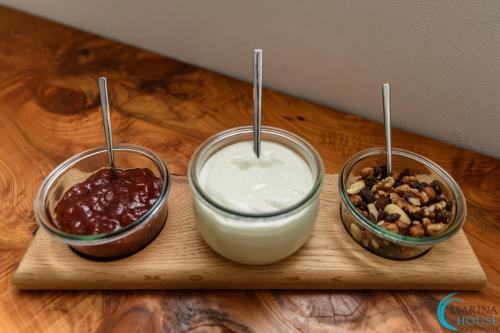 three bowls of yogurt and nuts on a wooden cutting board at B&B Marina House Porto Ercole in Porto Ercole