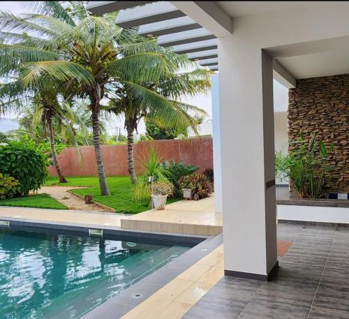 a swimming pool in a house with palm trees at Aux chants d'oiseaux in Ngaparou