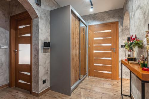 a bathroom with a walk in shower and wooden doors at Dream Holiday z Sauna i jacuzzi Lovely Krynica Zdrój in Florynka