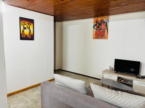 a living room with a couch and a tv at T2 confortable à Acajou Lamentin in Le Lamentin