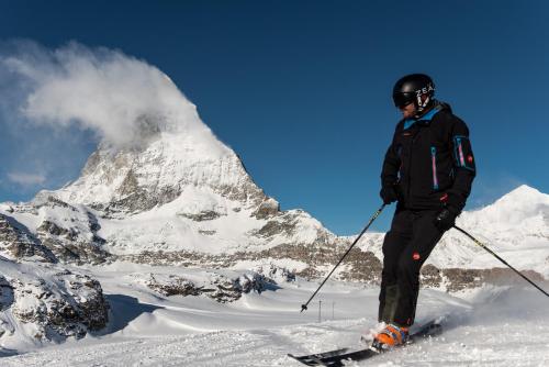 a man on skis standing on a snowy mountain at Le Petit CHARME-INN in Zermatt