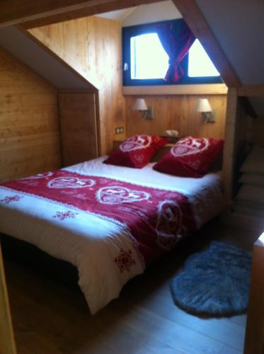 une chambre avec un lit avec des oreillers rouges et une fenêtre dans l'établissement Le Valier chalet le Desman, à Ustou