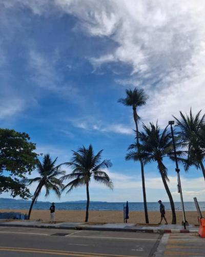 people walking on the beach with palm trees at MaHaNa Hostel Pattaya in Jomtien Beach