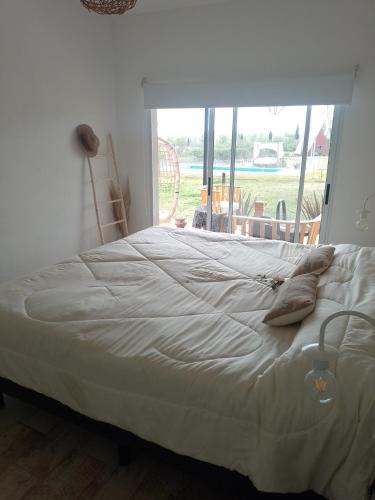 una cama en una habitación con una ventana grande en Los colibries, en San Pedro