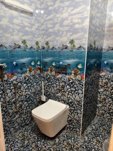 a bathroom with a toilet and a wall with a painting at SG Mahal & Rooms in Kanyakumari