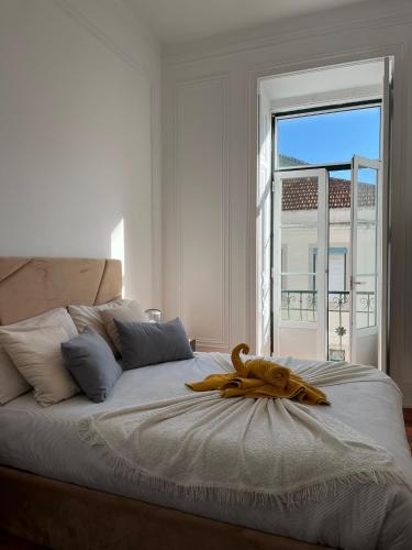 a white bedroom with a large bed with a window at Garden Campo de Ourique Guest House - Hostel in Lisbon