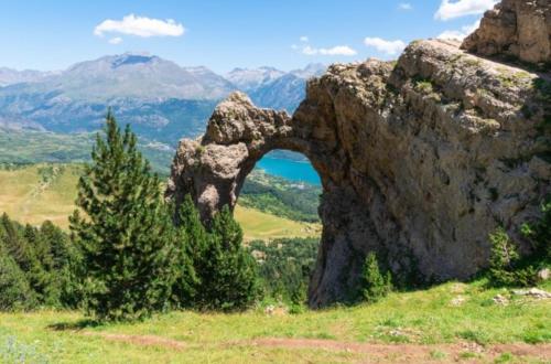 a rock formation on a hill with a lake and mountains at EscarraSuite in Escarrilla