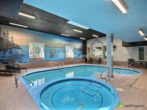 einen großen Pool in einem Zimmer mit Whirlpool in der Unterkunft Condos Memphrémagog in Magog-Orford