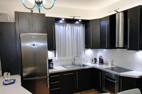 a kitchen with black cabinets and a stainless steel refrigerator at Malvazios Villas #3 in Gythio