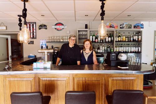 a man and woman standing at a bar at Gîte - Auberge du Midi in Saint-Antoine