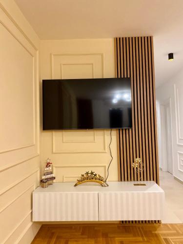a tv hanging on a wall with a white table at Pale apartman Gold in Pale