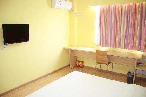 a room with a bed and a desk and a television at 7Days Inn Wuxi Shuofang Airport in Wuxi