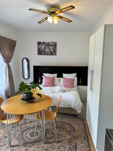Un dormitorio con una cama y una mesa y sillas. en The Herby Taylor Guest House, en Vereeniging