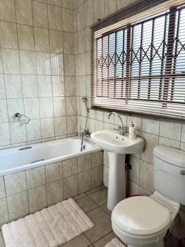 a bathroom with a toilet and a sink and a tub at The Herby Taylor Guest House in Vereeniging