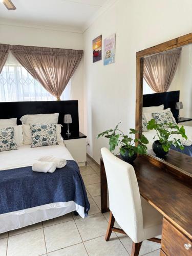 a bedroom with a bed and a desk and a mirror at The Herby Taylor Guest House in Vereeniging