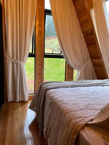 a bedroom with a bed and a large window at Cabana Santo Rancho Treze Tílias in Treze Tílias