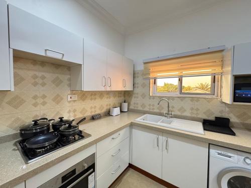 a kitchen with white cabinets and a stove and a sink at Anns Luxurious Apartments 3 in Accra