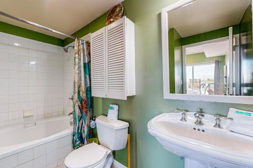 Un baño con lavabo, inodoro y espejo. en Emerald Isle 0107, en Pensacola Beach