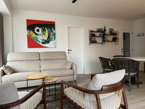 un salon avec un canapé et une table dans l'établissement Dzee Appartement frontaal zeezicht en gratis parking, à Coxyde