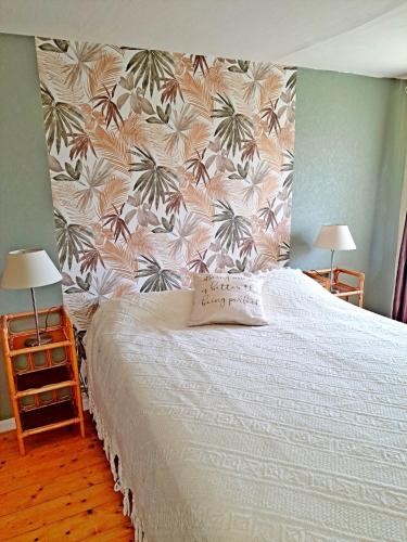 - une chambre avec un lit orné d'un mur fleuri dans l'établissement Cottage l'Atelier, aire de loisirs avec piscine, à Marigny