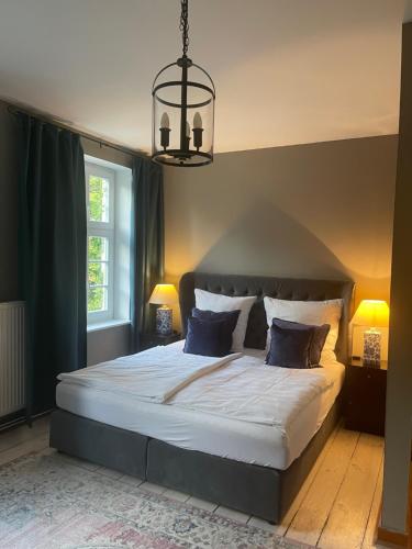 a bedroom with a large white bed with a chandelier at Saniertes Gutshaus mit Komfort und privater Sauna in Neu Gaarz