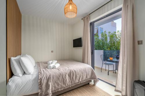 a bedroom with a bed and a balcony with a table at Fly & Stay in Artemida