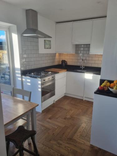a kitchen with white appliances and a wooden floor at Family home with garden in Hersham