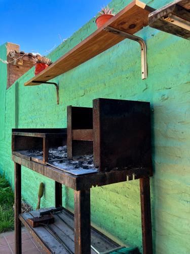 a wooden table with a stove in front of a building at Acogedora casa cerca de la Laguna, con pileta in Chascomús