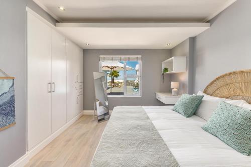 a bedroom with a large white bed and a window at Melkbos Beachfront Villa in Cape Town