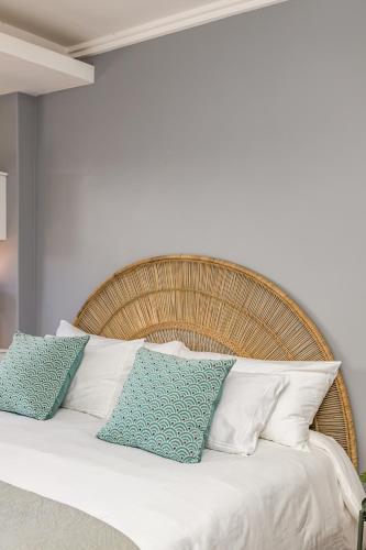 a bed with white pillows and a wooden headboard at Melkbos Beachfront Villa in Cape Town