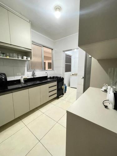 duża kuchnia z białymi szafkami i sprzętem AGD w obiekcie Brilho do mar Enseada w mieście Guarujá