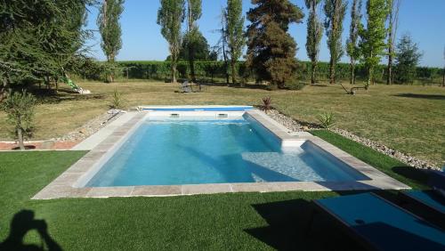a swimming pool in a yard with a grass field at Maison pour 4/ 6 personnes les hirondelles in Saint-Vivien-de-Monségur