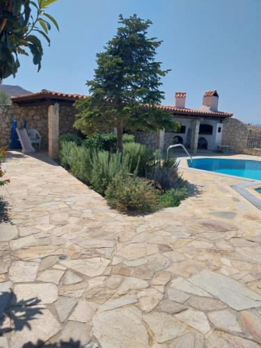 a stone patio with a tree and a swimming pool at The Three Graces in Karteros