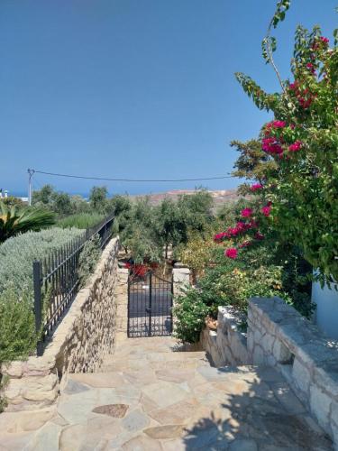 a garden with a stone fence and pink flowers at The Three Graces in Karteros