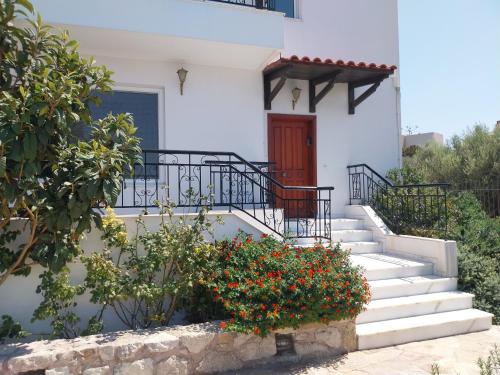a white house with stairs and a red door at The Three Graces in Karteros