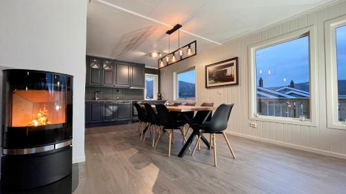 a dining room with a fireplace and a table and chairs at Sandersstua 2, luxury family apartment with private whirlpool in Stamsund in Vestvågøya