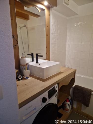 La salle de bains est pourvue d'un lavabo blanc et d'une baignoire. dans l'établissement Résidence Garden city, vue lac, à Lugrin