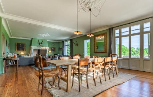 une salle à manger avec des murs verts, une table et des chaises dans l'établissement Manoir de Valmont - Court de tennis, à Hotot-en-Auge