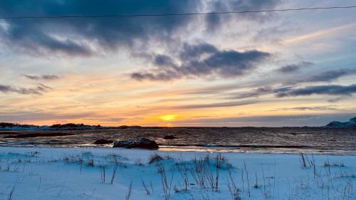 a sunset on the beach with the sun setting at Sandersstua 2, luxury family apartment with private whirlpool in Stamsund in Vestvågøya