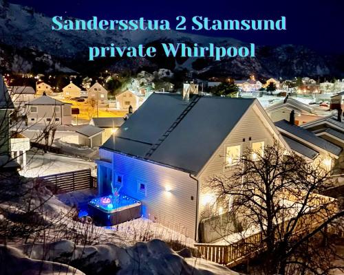 a white barn with blue lights on it at night at Sandersstua 2, luxury family apartment with private whirlpool in Stamsund in Vestvågøya