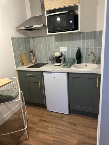 une petite cuisine avec un évier et un micro-ondes dans l'établissement La Suite Émeraude - Cosy, chic et bord de mer, à Cabourg