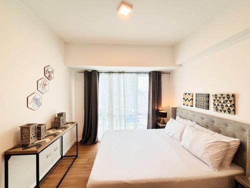 a bedroom with a large white bed and a window at Abreeza Place Cozy Condo in Davao City