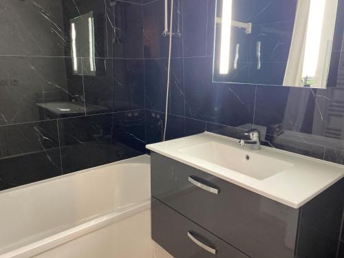 une salle de bain avec un lavabo, un miroir et une baignoire dans l'établissement Appart rénové cœur station, skis aux pieds, parking, animaux admis - FR-1-513-98, à Courchevel