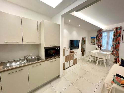 une cuisine avec des armoires blanches et une table dans une pièce dans l'établissement Le Cap, beau trois pièces au coeur de la vieille ville, à Menton