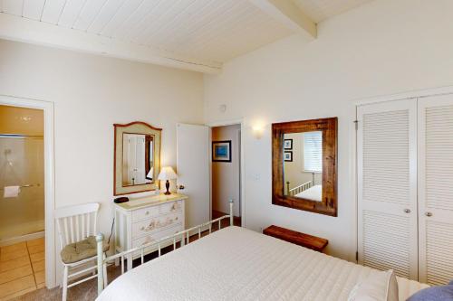 a white bedroom with a bed and a mirror at Oceanfront Dream in Cayucos