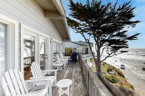 a porch with white chairs and a tree and the ocean at Oceanfront Dream in Cayucos