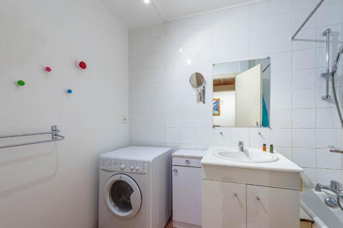 une salle de bain blanche avec une machine à laver et un lavabo dans l'établissement Smartstay massif mont blanc - Saint gervais, à Saint-Gervais-les-Bains