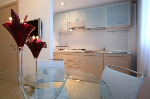 a kitchen with a glass table and a kitchen with white cabinets at Le Onde Resort in Viterbo