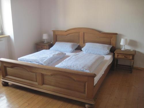 a wooden bed with two pillows and two tables at Ferienwohnung Zum Landsknecht in Lissendorf